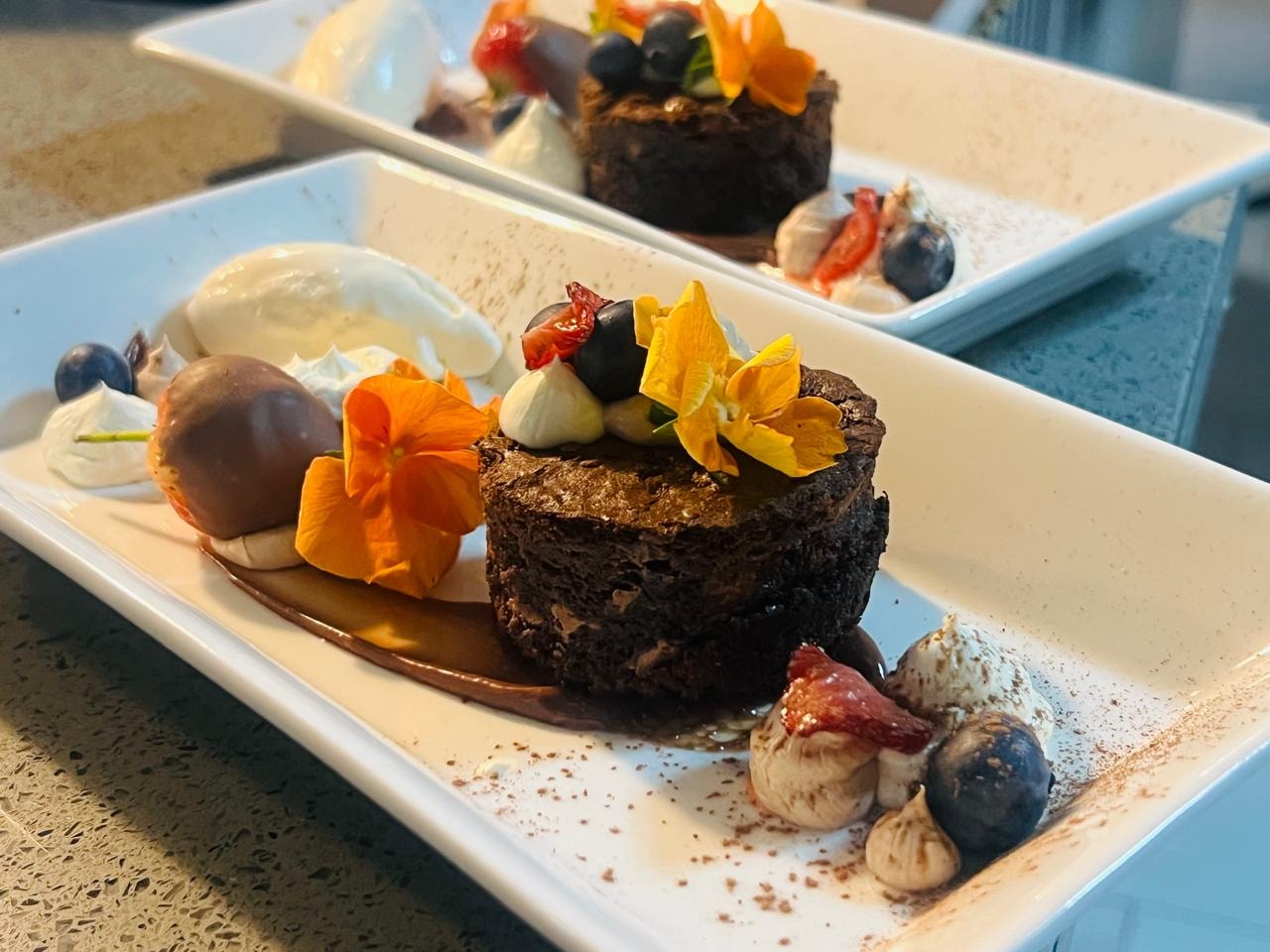 Chocolate dessert plated with edible flowers and berries